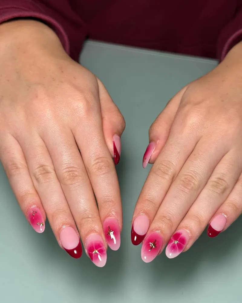 Pale pink nails with a cherry red aura glow and tiny gems